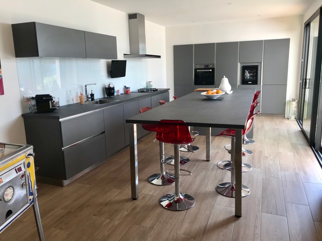 Îlot central de cuisine équipé d'une plaque de cuisson et d'un coin repas, dans une cuisine ouverte